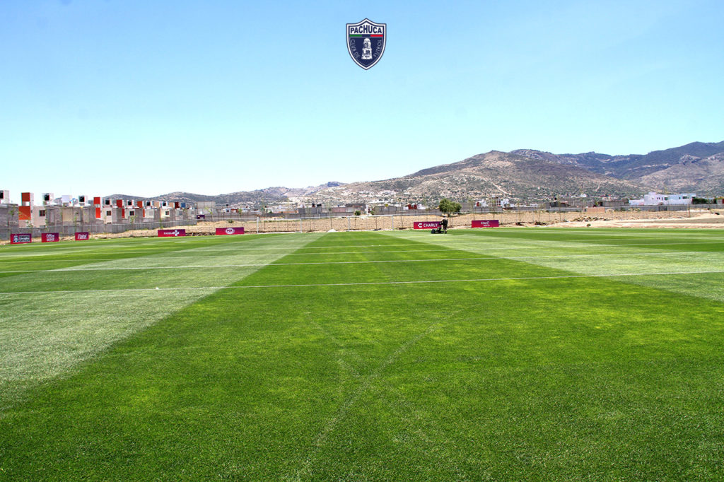 Cancha de pasto natural equipada con banquillos para dos equipos para uso de la Universidad del Futbol, primer equipo -femenil- y fuerzas básicas.