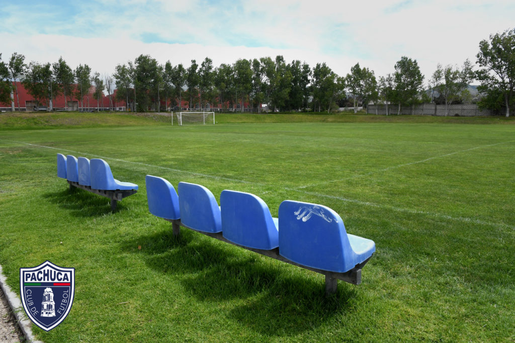 Cancha de pasto natural equipada con banquillos para dos equipos para uso de la categoría Sub – 17 de las fuerzas básicas.