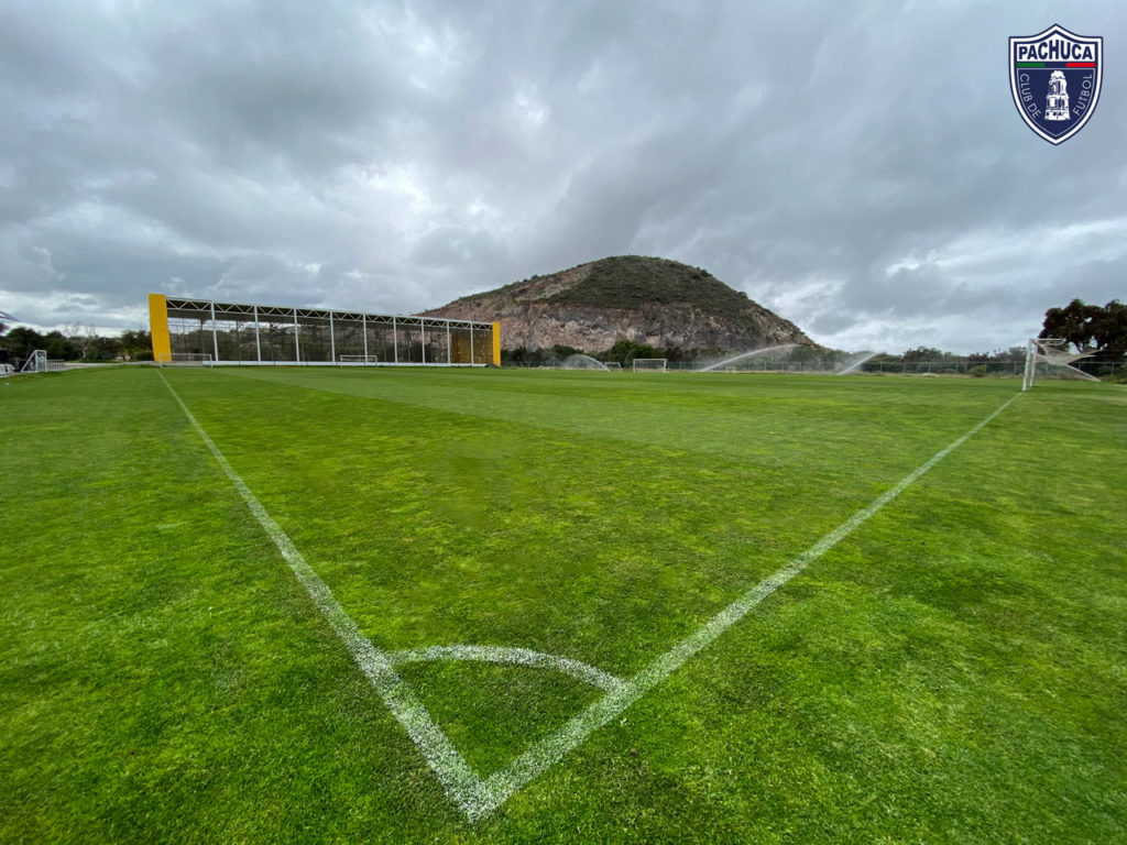 Cancha de pasto natural equipada con banquillos para dos equipos para uso de la Universidad del Futbol y primer equipo.