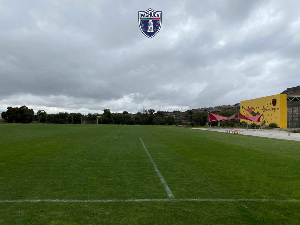 Cancha de pasto natural equipada con banquillos para dos equipos para uso de la Universidad del Futbol y primer equipo.